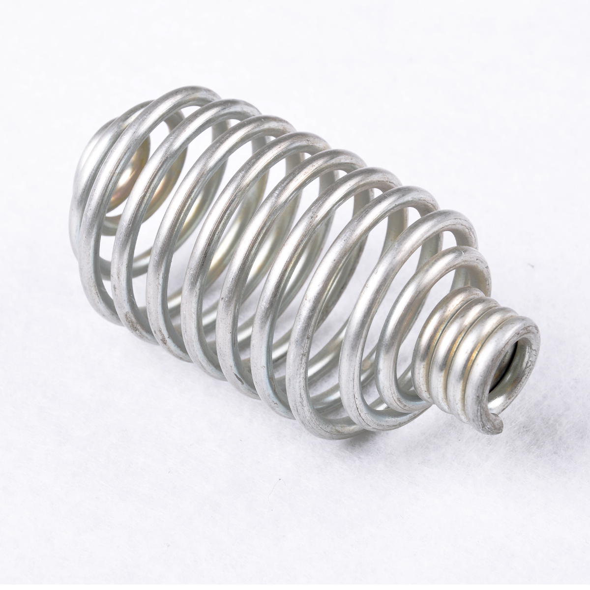 Silver barrel-shaped spring with tight coils at the narrow end