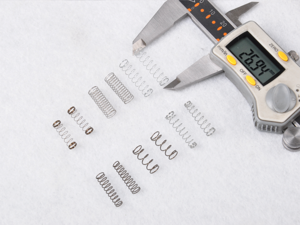 Small springs being measured with a digital caliper.
