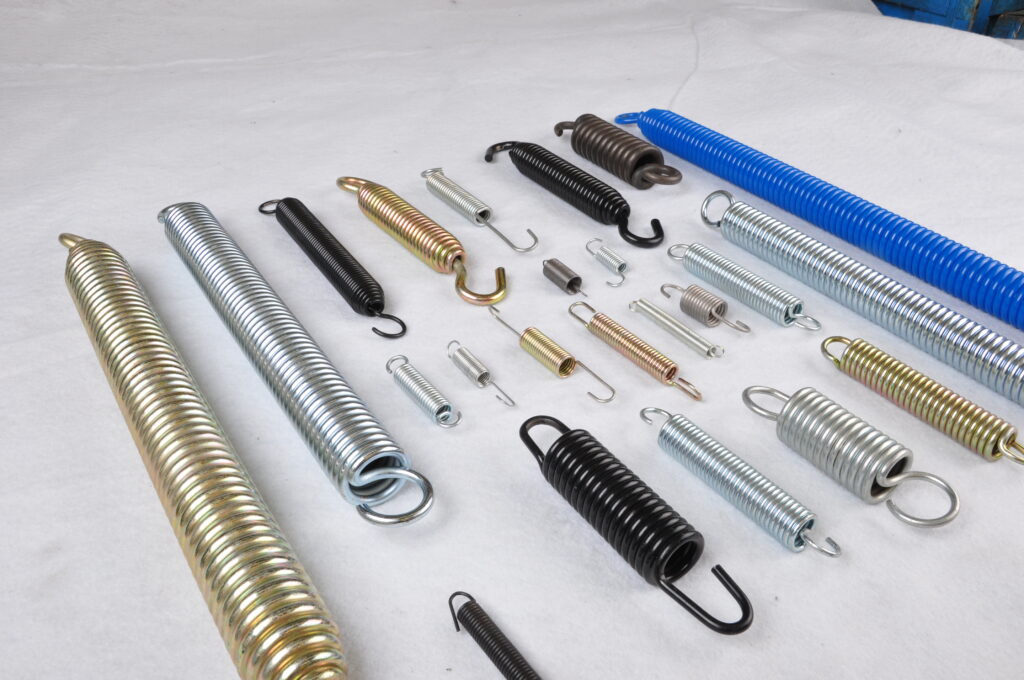 A selection of extension springs in yellow zinc, bright zinc, black and blue finishes, with machine hooks, extended hooks and full loops