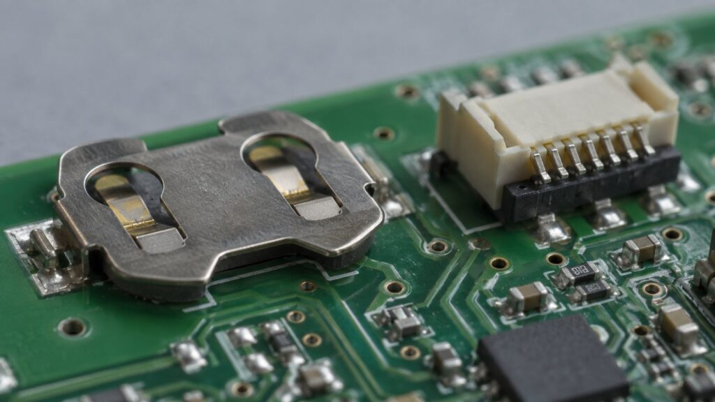 Illustration: a circuit board with a coin-cell battery holder and a small connector.